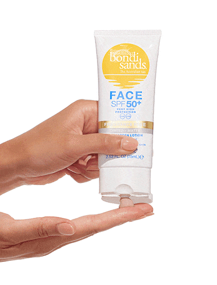 A hand squeezes BondiSandsEU Face SPF 50+ Tinted & Matte Sunscreen Lotion from a white and yellow tube onto fingers, demonstrating product application.